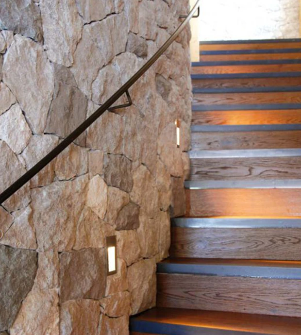 Parete in pietra naturale accanto a scala moderna in legno
